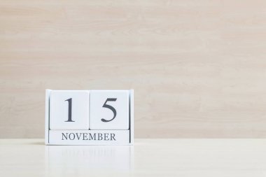 Closeup bulanık kahverengi ahşap masa ve kopya alanı, takvim, seçici odak ile ahşap duvar dokulu arka plan üzerinde siyah 15 Kasım kelime ile beyaz ahşap takvim yüzey