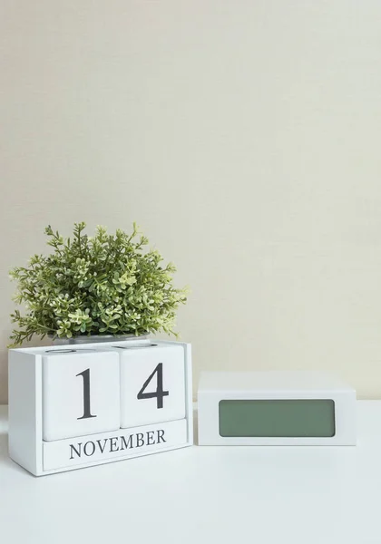 Calendario de madera blanca con negro 14 palabra de noviembre con reloj y planta sobre escritorio de madera blanca y fondo de pantalla crema textura, enfoque selectivo en el calendario — Foto de Stock