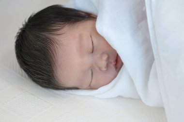 Yatakta rahat bir şekilde uyuyan bir bebeği yakından çek.