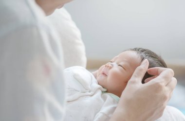 Annesinin kollarında bir bebek.