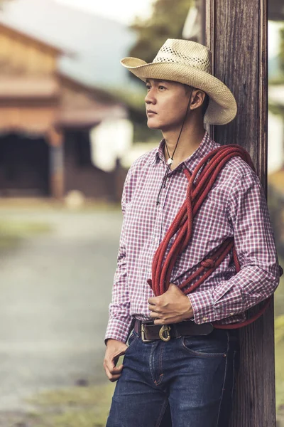 Guapo joven con sombrero de vaquero de pie pensando — Foto de Stock