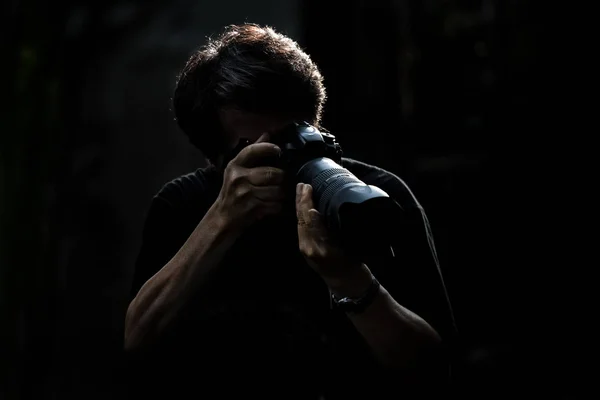 Фотограф чоловіки в дії з камерою і дивитися на чорну спину — стокове фото