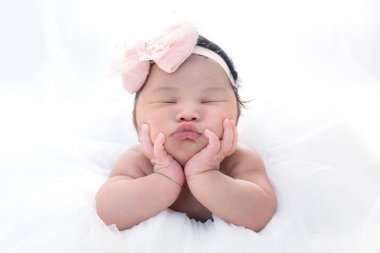 Newborn 7 day old baby girl on his white bed relaxing clipart