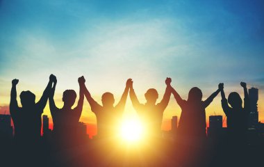 Grup iş ekibinin silueti ellerini havaya kaldırıyor.