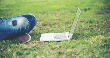 woman sit to use computer laptop on green grass at public park
