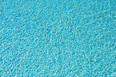 Mavi yüzme havuzu, güneşi yansıtıyor.