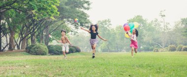 group of kids running in the spring field at public park