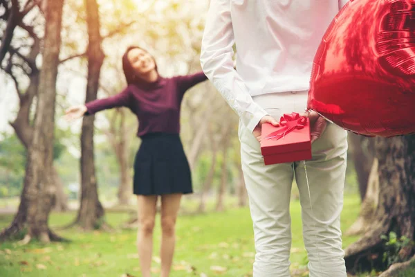 Jovem feliz asiático casal surpresa dom vermelho caixa no público parque — Fotografia de Stock