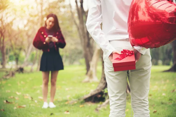 Mladý šťastný asijské pár překvapení dárek červená box na veřejné park — Stock fotografie