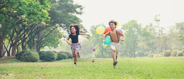 Two kids running in the spring field at public park — Stockfoto