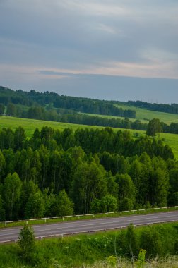 Yaz kıpkırmızı gün batımı. Gökyüzü kıpkırmızı. Güneş batarken kestane rengi bulutlar. Günbatımında yeşil halı.