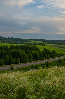 Yaz kıpkırmızı gün batımı. Gökyüzü kıpkırmızı. Güneş batarken kestane rengi bulutlar. Günbatımında yeşil halı.