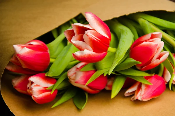red white tulips on wooden boards. Bouquet of tulips in kraft paper