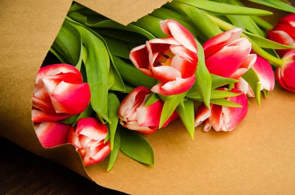 red white tulips on wooden boards. Bouquet of tulips in kraft paper