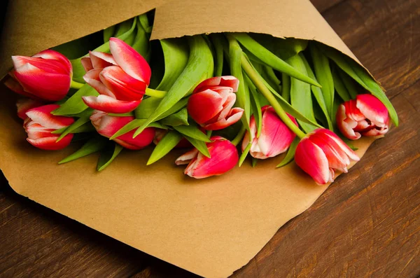 red white tulips on wooden boards. Bouquet of tulips in kraft paper