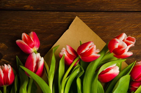 red white tulips on wooden boards. Bouquet of tulips in kraft paper