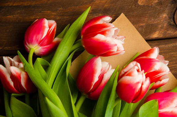 red white tulips on wooden boards. Bouquet of tulips in kraft paper