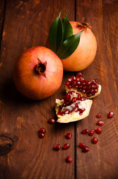 сочный гранат на деревянных досках .cut в куски спелых гранатов. Гранат созрел. спелые семена граната. свежие сочные листья
