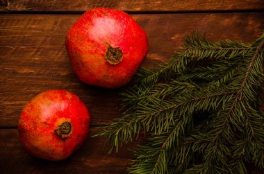 Tahta tahtalarda sulu nar. Taze yeşil köknar dalı. Tahta üzerinde olgun nar..