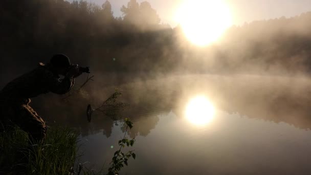 Мужчина фотографирует утренний туман. Теплый летний пейзаж — стоковое видео