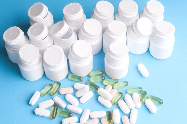 Wiele pigułki i tabletki na białym tle na jasno niebieskim tle — Zdjęcie stockowe