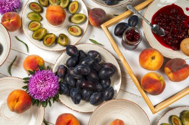 Renkli meyve mor, kırmızı ve turuncu arka planda kase kümesi. Erik, şeftali, karpuz dilimli beyaz masa üstü