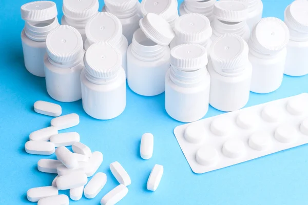 Wiele pigułki i tabletki na białym tle na jasno niebieskim tle — Zdjęcie stockowe