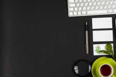 Ofis siyah resepsiyon masası beyaz bilgisayar, boş kartvizit, çiçek, kahve fincanı ve kalem.