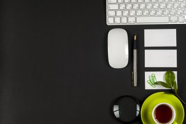 Ofis siyah resepsiyon masası beyaz bilgisayar, boş kartvizit, çiçek, kahve fincanı ve kalem.