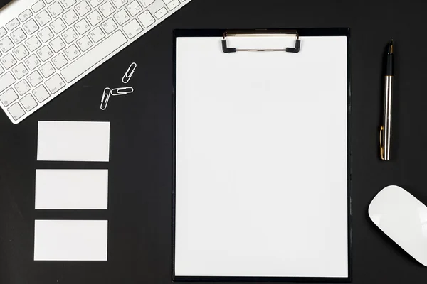 Mesa de escritorio negra de oficina con computadora blanca, tarjeta de visita en blanco, flor, taza de café y pluma . —  Fotos de Stock
