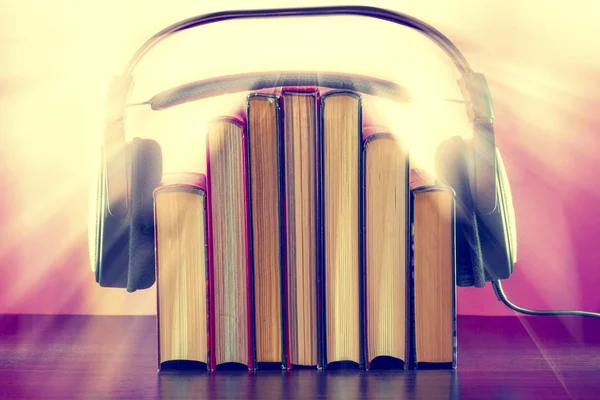 Kitap ve ahşap bir masa üzerinde bir audiobook kavram olarak kulaklık.