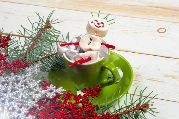 Weihnachtskarte mit lustigem Marshmallow-Schneemann in grüner Tasse, Baum — Stockfoto