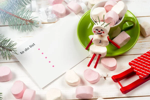 Weihnachtskarte mit lustigem Marshmallow-Schneemann in grüner Tasse, Baum — Stockfoto