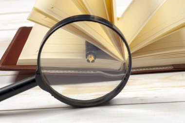 Açık kitap ve Büyüteç camı kompozisyonu. Okula dönüş, uzay kopyalayın. Eğitim arka plan.