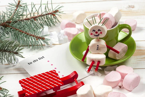 Рождественская открытка с веселым зефиром снеговик в зеленой чашке, елка — стоковое фото