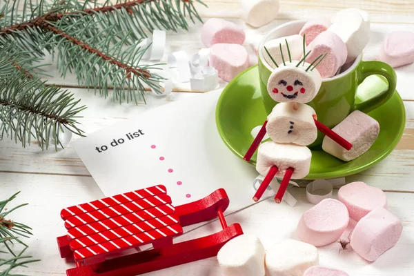 Weihnachtskarte mit lustigem Marshmallow-Schneemann in grüner Tasse, Baum — Stockfoto