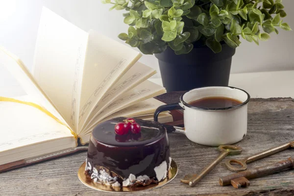Старые старинные книги, чашка чая, торт и ключи на деревенском деревянном столе — стоковое фото