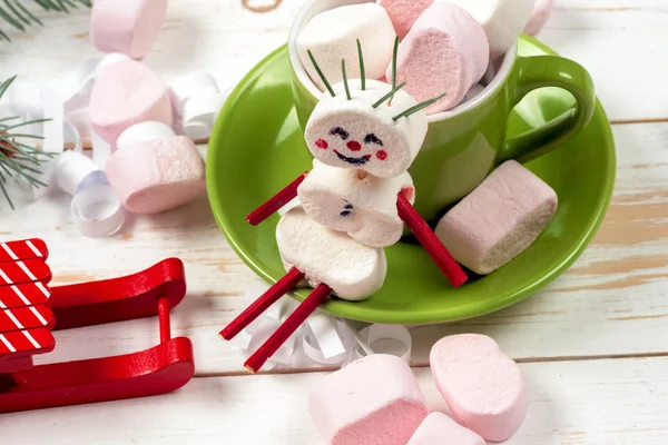 Weihnachtskarte mit lustigem Marshmallow-Schneemann in grüner Tasse, Baum — Stockfoto