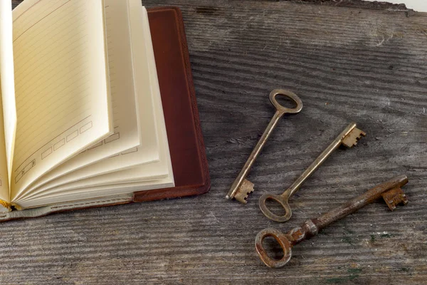 Antique book and old keys over rustic wooden background. — Stock Photo, Image