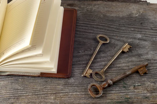 Antique book and old keys over rustic wooden background. — Stock Photo, Image