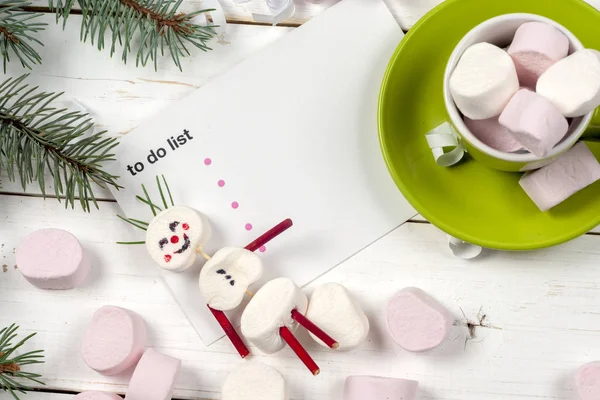 Weihnachtskarte mit lustigem Marshmallow-Schneemann in grüner Tasse, Baum — Stockfoto