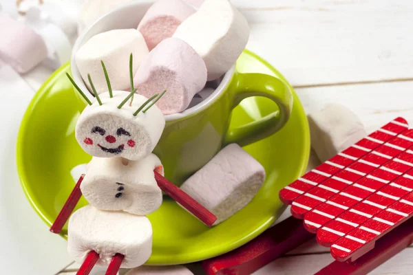 Weihnachtskarte mit lustigem Marshmallow-Schneemann in grüner Tasse, Baum — Stockfoto