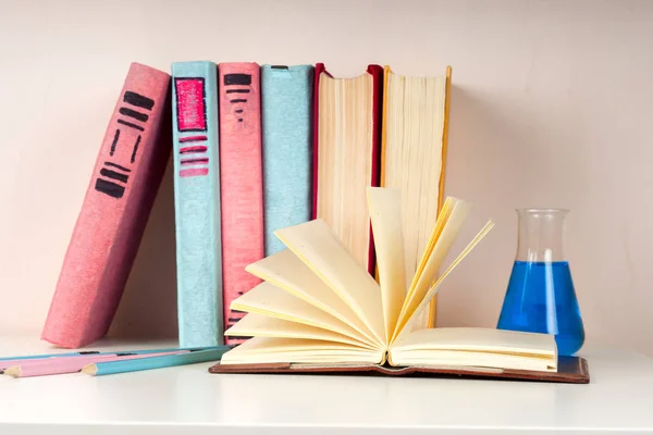 Open book, stack of colorful hardback books on light table. Back to school. Copy space for text — Stock Photo, Image