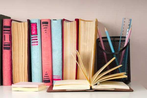 Offenes Buch, Stapel bunter gebundener Bücher auf hellem Tisch. zurück zur Schule. Kopierraum für Text — Stockfoto