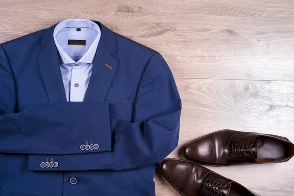 Плоский набор классической мужской одежды, такой как синий костюм, рубашки, коричневые туфли, пояс и галстук на деревянном фоне . — стоковое фото