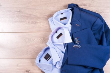 Düz ahşap zemin üzerine mavi takım elbise, gömlek, kahverengi ayakkabı, kemer ve kravat gibi klasik erkek giysi set koymak.