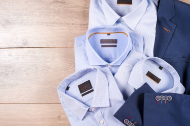 Klasik erkek kıyafetleri - mavi takım, gömlekler, kahverengi ayakkabılar, kemer ve kravat ahşap arka planda.