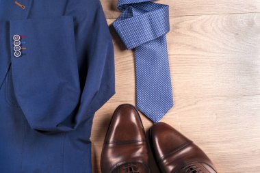 Klasik erkek kıyafetleri - mavi takım, gömlekler, kahverengi ayakkabılar, kemer ve kravat ahşap arka planda.