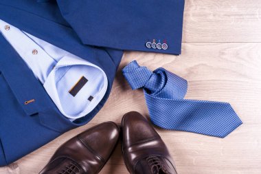 Klasik erkek kıyafetleri - mavi takım, gömlekler, kahverengi ayakkabılar, kemer ve kravat ahşap arka planda.