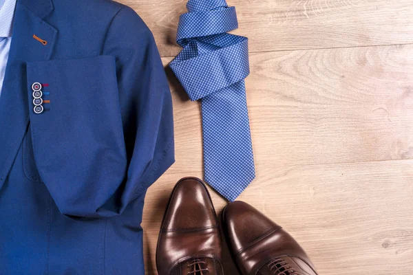 Klasik erkek kıyafetleri - mavi takım, gömlekler, kahverengi ayakkabılar, kemer ve kravat ahşap arka planda.